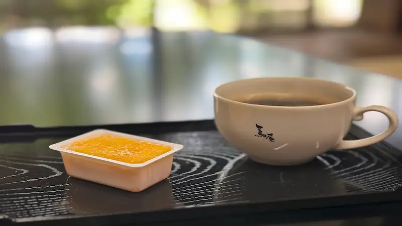 按針の館の喫茶スペースで提供されるコーヒーとカスドース。黒いお盆に和菓子とコーヒーカップが並ぶ
