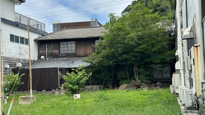 長崎県平戸市の按針の館を裏側から撮影した写真。木造の建物と庭の緑、周囲の建物が調和する風景