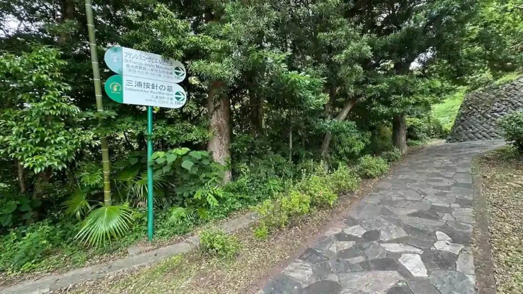 平戸市で三浦按針の墓とフランシスコ・ザビエル記念碑への案内看板が立つ遊歩道。木々に囲まれた石畳の小道