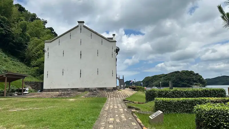平戸市のオランダ商館を側面から撮影。白い建物と海沿いの遊歩道、芝生の庭園が広がる