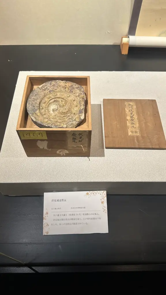松浦史料博物館に展示されている伏見城の金箔瓦。木箱に収められた金箔が施された瓦と解説パネル