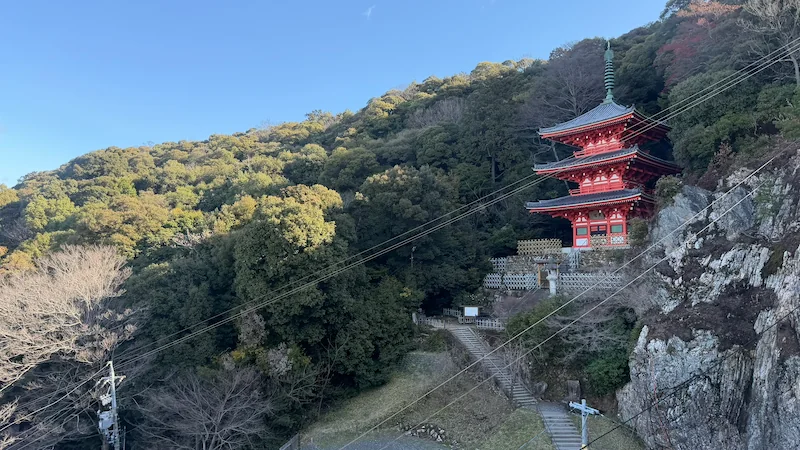 The vermilion three-story pagoda in Gifu Park, set against the green slopes of Mount Kinka