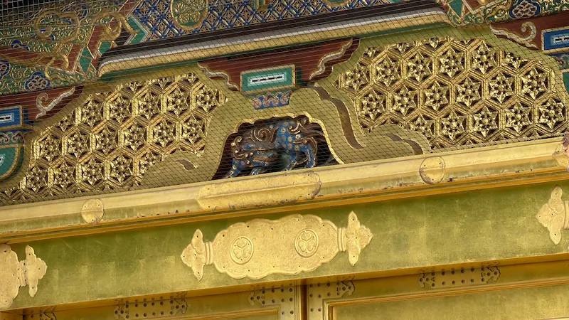 Close-up of the wooden carvings on the Karamon Gate at Ueno Toshogu Shrine. Gold and blue coloring remain visible.