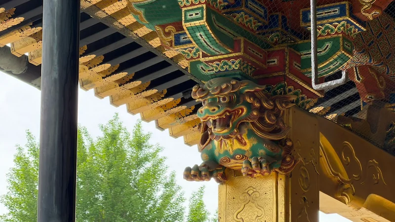 Green and gold shigami lion at Ueno Toshogu Shrine’s Kinshikiden. A decorative pillar-top carving supporting the roof.