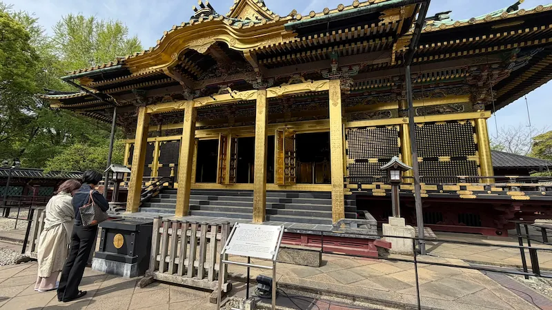 Full view of Ueno Toshogu Shrine’s Kinshikiden. Visitors gather in front of the open doors and look up at the shrine building.
