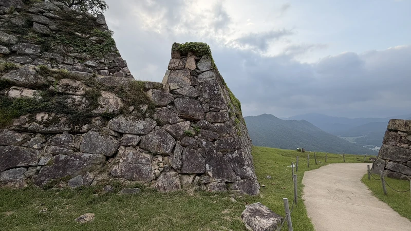 Stone walls at Takeda Castle Ruins rising against a backdrop of mountains.
