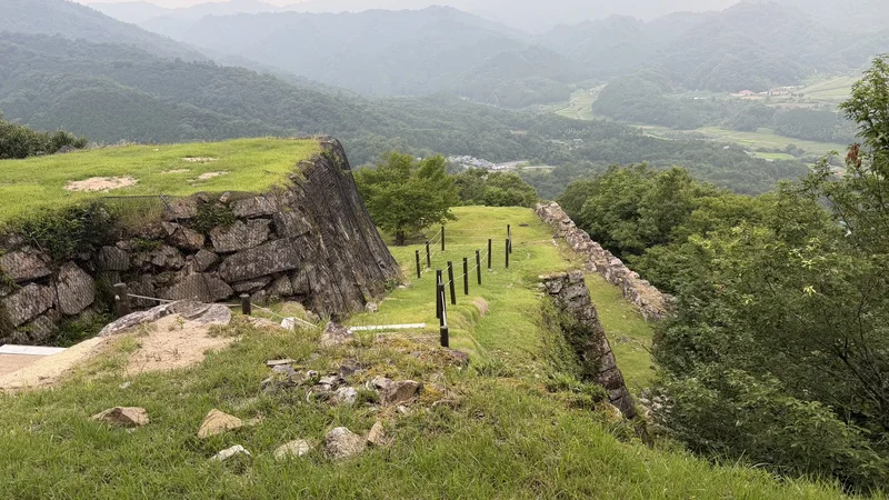 Stepped stone walls around Hanayashiki Bailey Site, with a valley visible below.