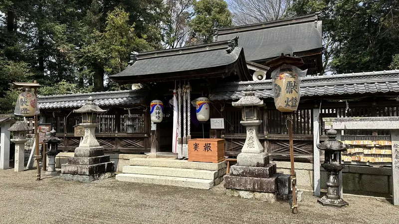 A front view of the inner sanctuary at Ikutsuhikone Shrine, lined with stone lanterns, hanging lanterns, and an ema votive-picture rack.