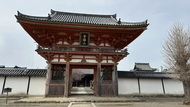The vermilion two-story gate at the entrance to Jogon-in Temple, with a plaque reading the mountain name 'Konshozan' above the upper story.
