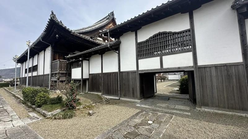 A hall and white-walled, corridor-like structure on the Jogon-in Temple grounds, with the inner precinct visible through a low side gate.