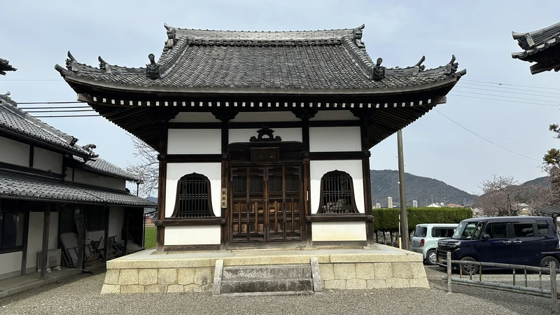 A small irimoya-style (hip-and-gable) hall on the Jogon-in Temple grounds, seen from the front with its white walls, timber frame, and curved tiled roof.