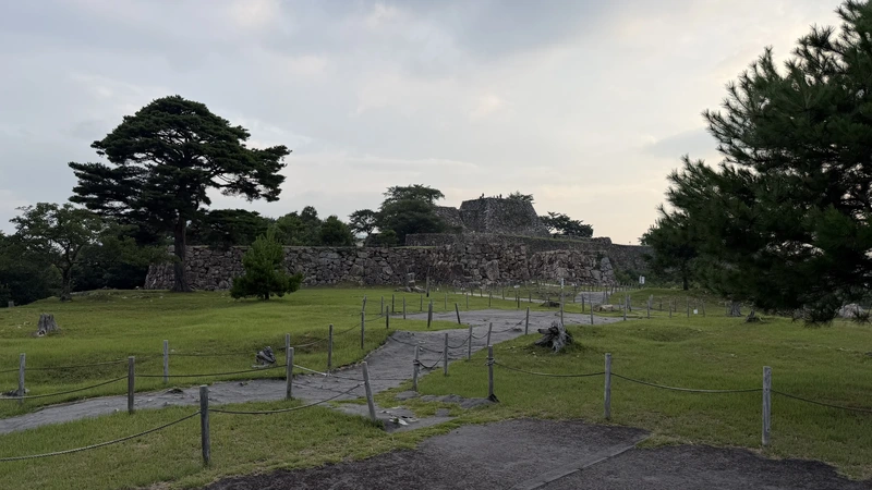 A view over the stone walls from the open ground at Minami-Senjo, with the viewing path curving gently through the bailey.