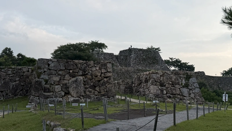 A long run of stone walls and the viewing path around Minami-Senjo, conveying the scale of the mountain castle's fortifications and layout.