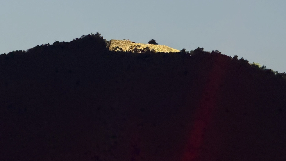 Takeda Castle Ruins brightly lit at the top of the mountain, seen from a distance against the night sky.