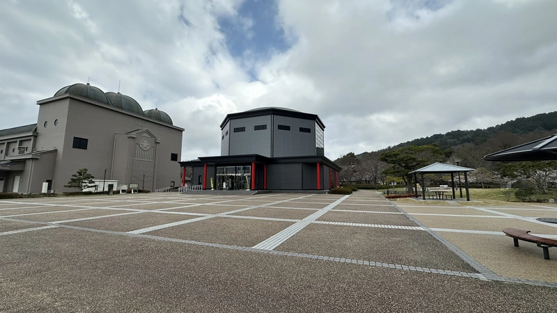 The exterior of Nobunaga no Yakata Museum, with a white exhibition hall and a black-toned entrance building lined up beyond the plaza.