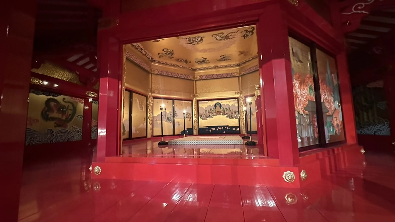 The interior of the reconstructed 5th floor of the Azuchi Castle tenshu, an octagonal space enclosed by vermilion pillars and painted walls.