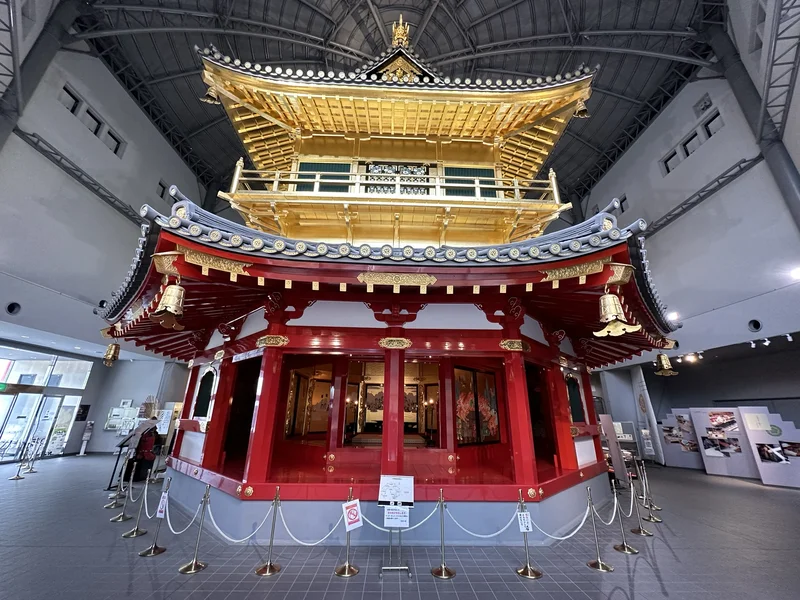 A full view of the reconstructed 5th and 6th floors of the Azuchi Castle tenshu, with a golden pavilion set atop a vermilion octagonal story.