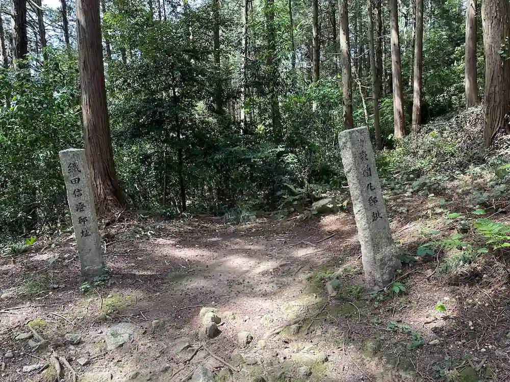 Stone markers for the Oda Nobuzumi and Mori Ranmaru mansion sites standing among the trees at Azuchi Castle ruins