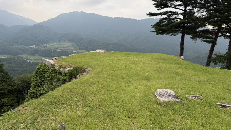 The lawn and edge of Sannomaru, with the valley and mountains below, showing the extent of this flat mountaintop bailey.