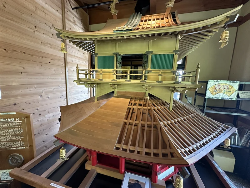 A model of the Azuchi Castle tenshu (main tower) on display at Jonavikan, with its green-and-gold upper stories and wide overhanging roof reproduced in detail.