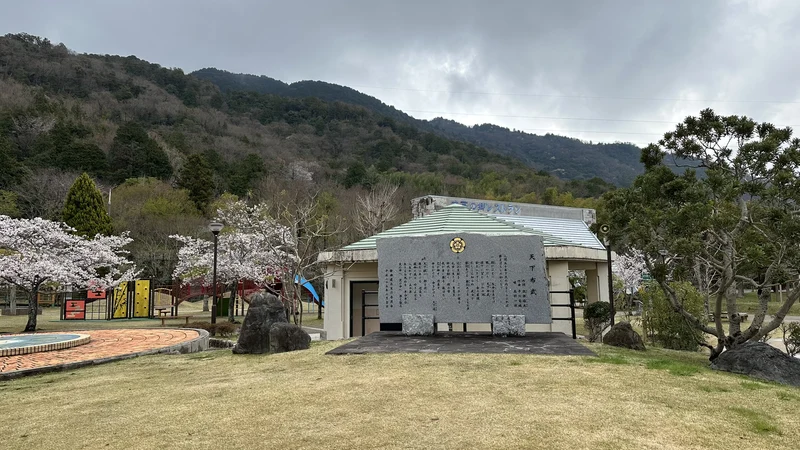 The 'Tenka Fubu' monument surrounded by cherry trees, with a large inscribed face recording the song's story.