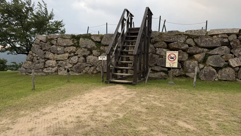 Wooden steps built into the stone wall of Tenshudai — the current route up to the top of the foundation.