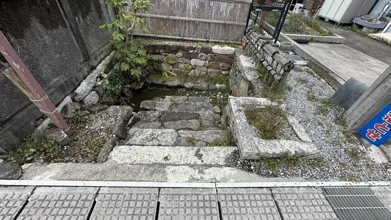 A view down onto the stonework at Ume-no-kawa, a small spring basin enclosed by stepped stone retaining walls.