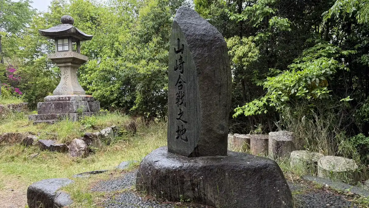 A stone marker reading Site of the Battle of Yamazaki and a stone lantern along the trail