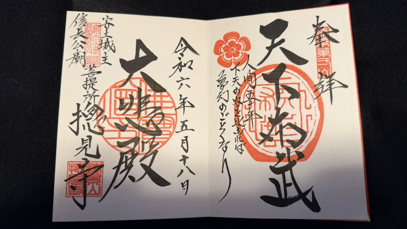 御朱印帳の見開きに記された二つの御朱印。右ページには織田木瓜紋と「天下布武」、左ページには「大悲殿」の墨書があり、複数の朱印が重ねられている。