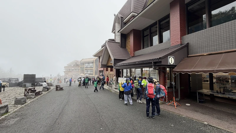 霧に包まれた五合目施設と登山者