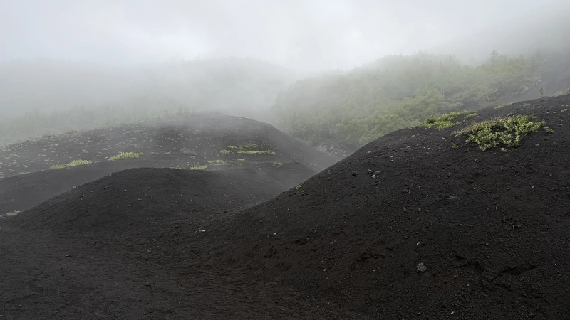 霧に包まれた黒い火山礫の盛り上がり
