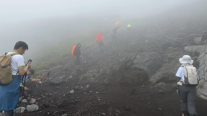 霧に包まれた岩場を登る登山者