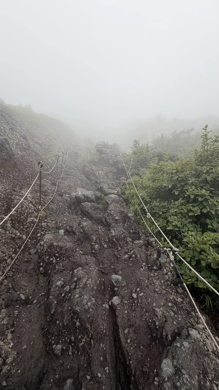 霧の中に続く急な岩場の登山道