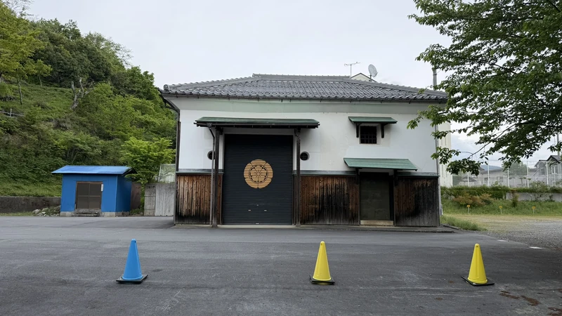 A white-walled building with a black door, on the shrine grounds