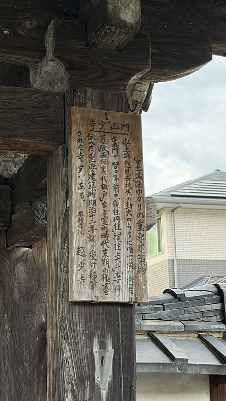 A wooden plaque mounted on a post of Chokoji Temple's gate, still bearing vertical lines of ink text.