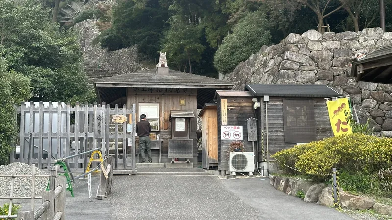 高い石垣の下に設けられた安土城跡の受付入口。料金所や注意表示が並んでいます。