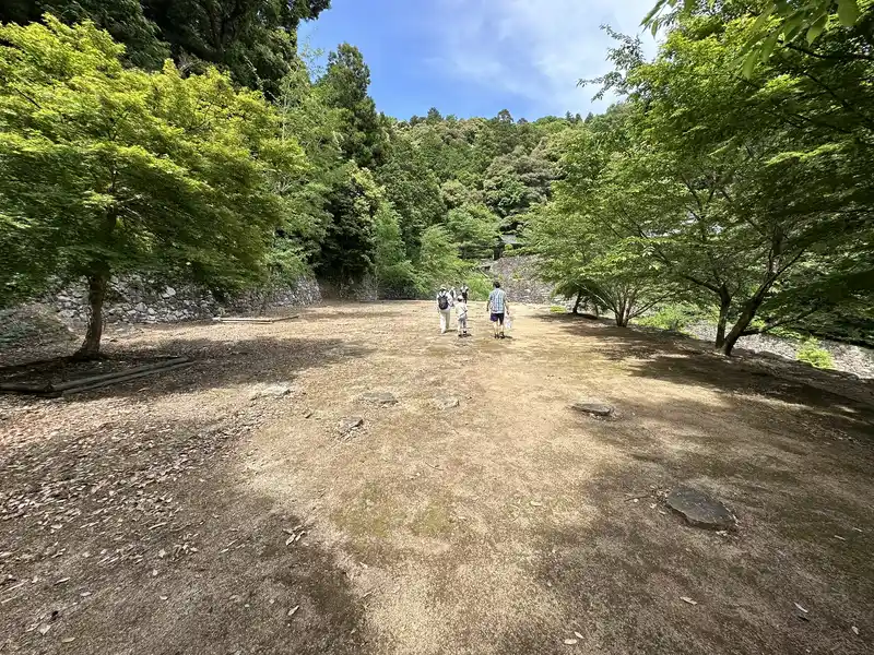 The wide flat terrace at the residence ruins traditionally attributed to Hideyoshi, enclosed by stone walls and trees.