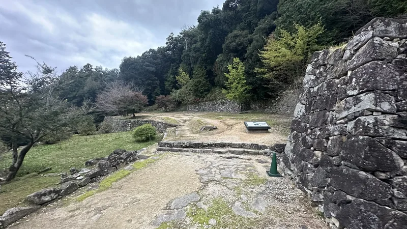 A view looking down over the terrace at the residence ruins traditionally attributed to Hideyoshi from the corner of a stone wall, showing its internal levels and pathways.