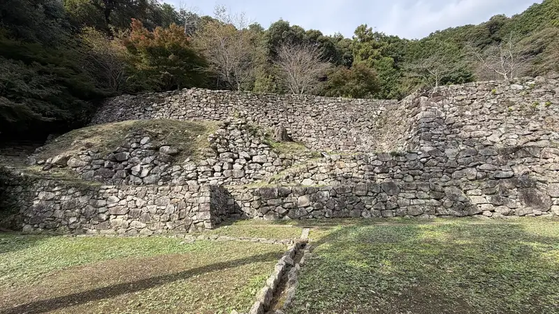 A stone wall at the residence ruins traditionally attributed to Hideyoshi, viewed head-on, with stone steps near the center leading up to the upper terrace.
