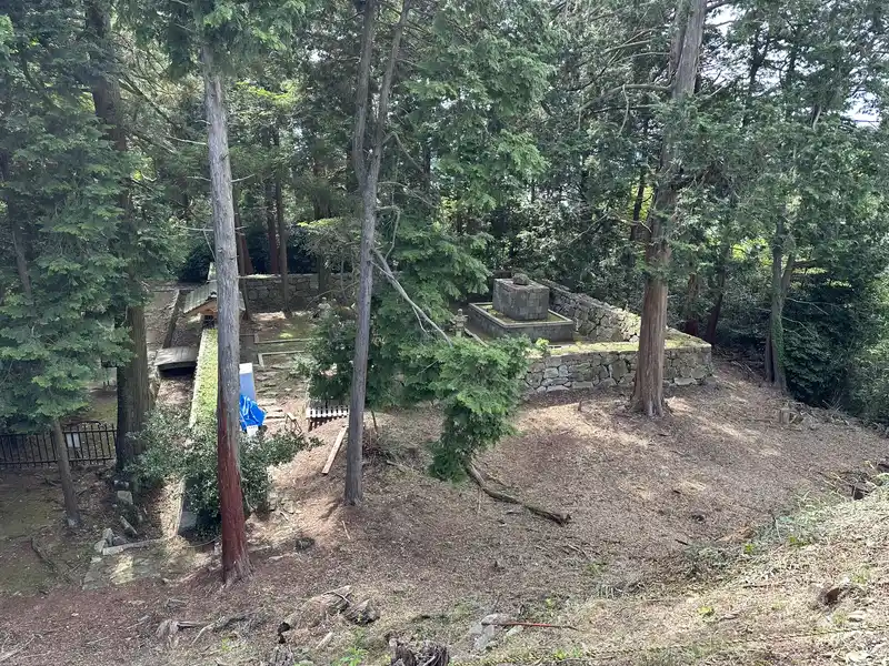 Nobunaga's Mausoleum surrounded by trees, seen from an elevated viewpoint. The stone-walled burial ground is visible.
