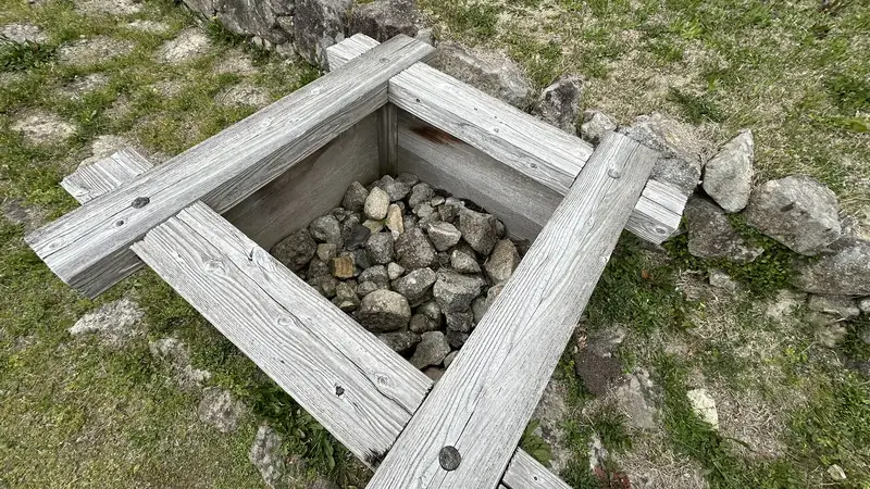 A preserved rectangular remain in the upper western enclosure, with stones packed inside a wooden frame.