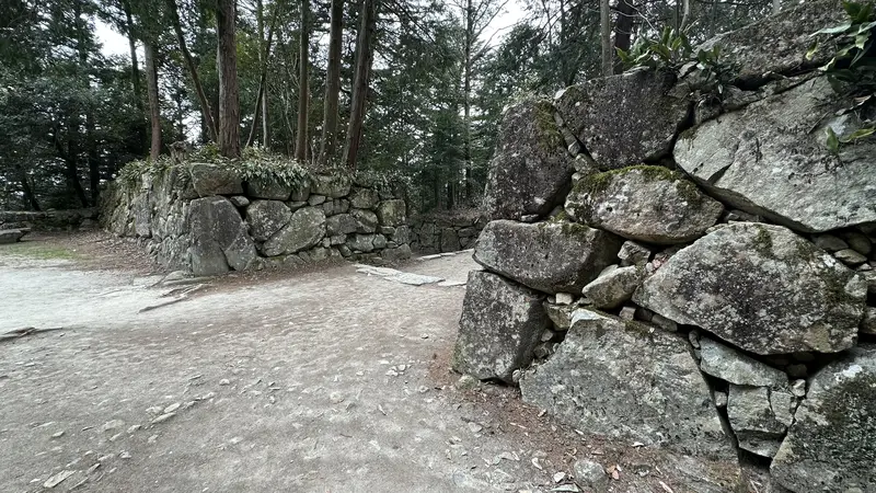 Kuroganemon Gate ruins at Azuchi Castle. The approach path zigzags between stone walls built from large natural stones.