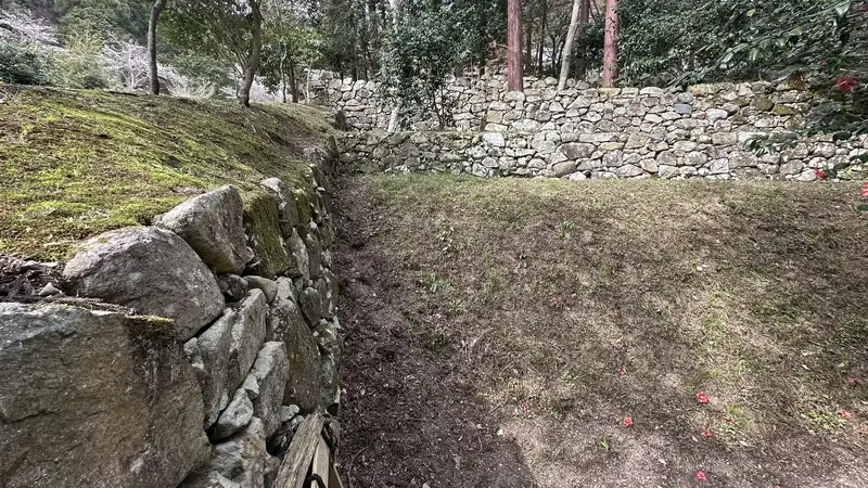 The terraced enclosures at the residence ruins traditionally attributed to Maeda Toshiie, with moss-covered stone walls lining the slope.
