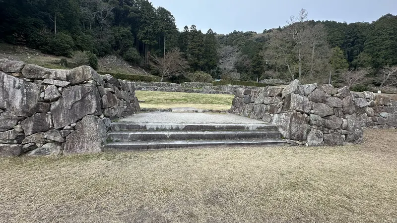 A front view of the masugata koguchi, with low stone steps set between stone walls on either side.