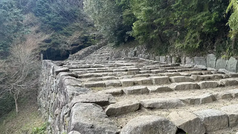 The wide stone stairway of Otemichi continuing up toward the summit, with stone walls and earthen ramparts visible on both sides.