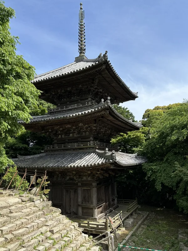 The Three-Story Pagoda of Sōken-ji amid fresh spring greenery, its three tiled roofs and spire set against a blue sky.