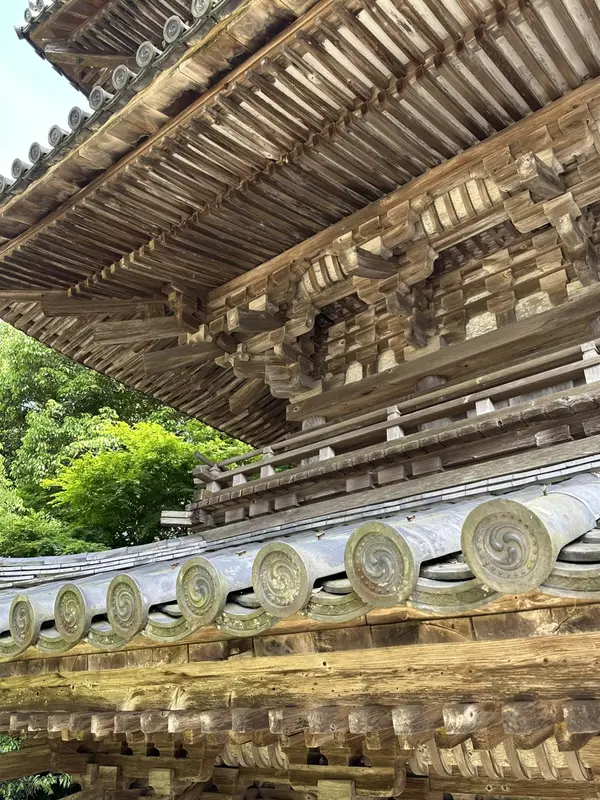 A detailed view looking up at the eaves of the Three-Story Pagoda, showing the layered timber bracketing and round roof tiles.