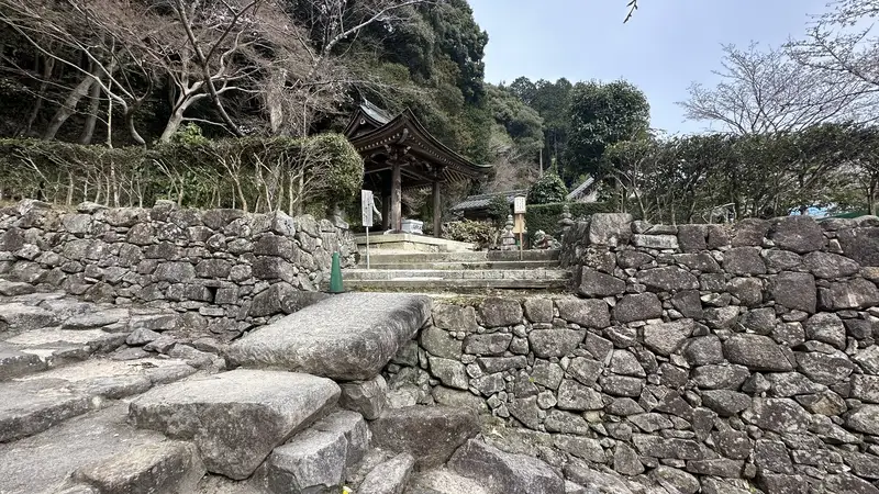 The stone walls and steps leading to the current entrance of Sokenji's temple grounds, with a small gate visible in the distance.