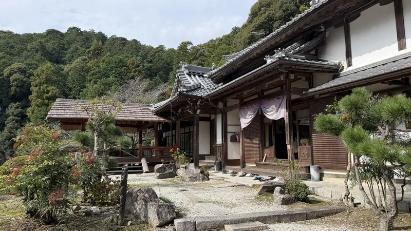 The current temple hall and garden at Sokenji, with trees and stones arranged in front of a white-walled building.