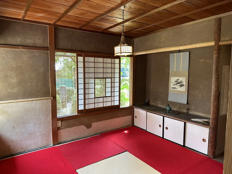 Sokenji's tea room with red cushions and tatami flooring, and a hanging scroll with a flower arrangement in the tokonoma alcove.